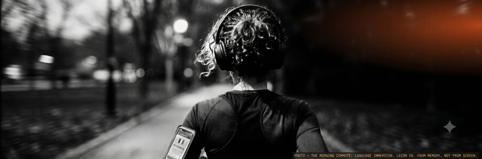 A runner from behind at dusk, headphones on, phone strapped to one arm