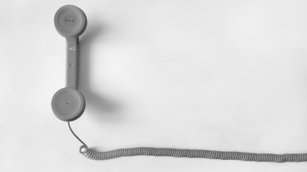 Czarno białe zdjęcie słuchawki od telefonu stacjonarnego i kabla.