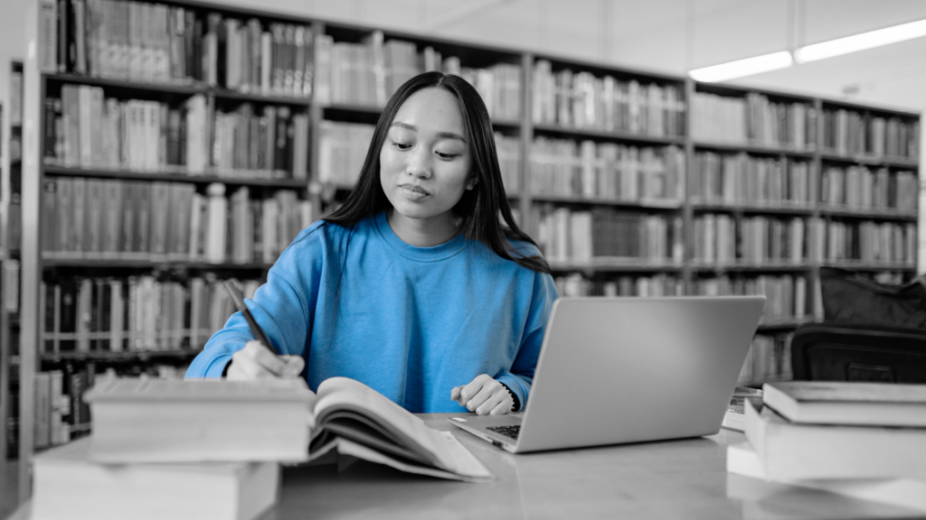 Dziewczyna w niebieskiej bluzie ucząca się w bibliotece.