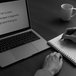 Student studying Scandinavian languages with full-sentence notes on laptop and notebook, black-and-white realistic photo.