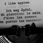 Black and white 16:9 close-up photograph of a typewriter merging with a modern keyboard, with fragments of sentences in English, Polish, German, Italian, French, and Spanish appearing and fading across the page and screen. The image symbolizes how Taalhammer transforms traditional language learning into adaptive, AI-driven full-sentence fluency.