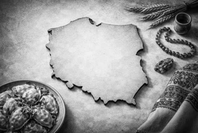 Black-and-white ultrarealistic 16:9 image showing the outline of Poland’s map centered on a textured surface, surrounded by subtle Polish cultural elements such as a plate of pierogi, a patterned folk textile, wheat stalks, and amber beads, with no text or labels visible.