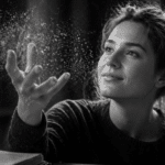 Black-and-white ultrarealistic image of a smiling person gently interacting with floating particles that subtly resemble words, symbolizing turning passive knowledge from a language learning app into usable language